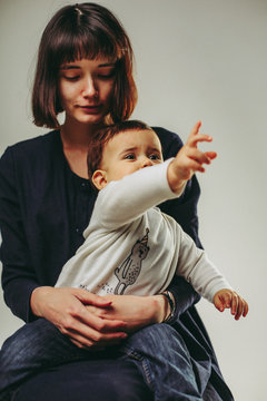 Portrait of sitting mother and baby crying and showing forward, emotional portrait, isolated