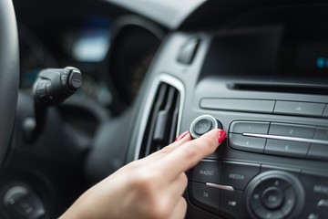 Woman adjusting volume on car radio