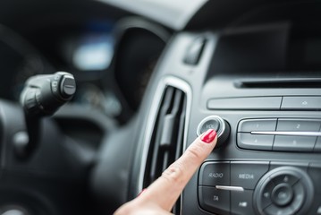 Obraz na płótnie Canvas Woman turning on car radio