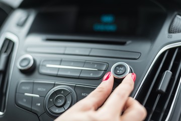 Woman changing frequency on car radio - obrazy, fototapety, plakaty