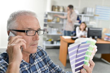 Man holding paint charts, talking on telephone