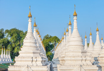 Fototapeta na wymiar Sandamuni Pagoda stupas tops in Mandalay, Myanmar. Central pagoda surrounded by 1774 white shrines, each housing a single marble slab with the teachings of the Buddha and located near Mandalay Hill.