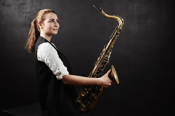 Young woman with saxophone on black background