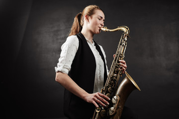 Naklejka na ściany i meble Young woman with saxophone on black background
