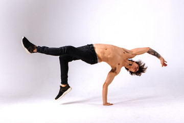 Strong powerful boy, man - freerunner, acrobat, tricker with muscular body in a jump upside down on...