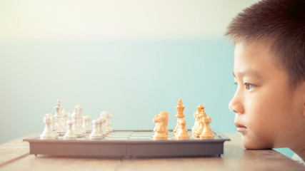 asian boy think or plan about chess game selective focus vintage style for education or business...