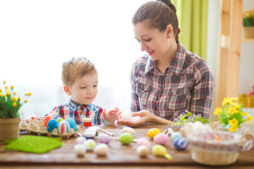 Mother and her son painting Easter eggs. Happy family preparing for Easter day