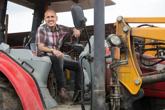 Senior positive operating modern tractor in livestock farm
