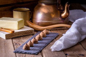 chocolate truffles on wooden table, with tea and butter block
