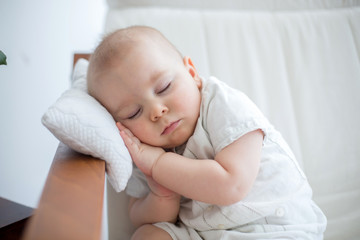 Little cute baby boy, sleeping in armchair with little pillow, cozy toddler