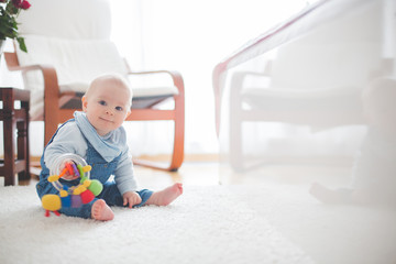 Cute little toddler baby boy, playing at home on the floor in bedroom