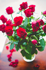 Close up of red roses in a vase on wooden rustic table