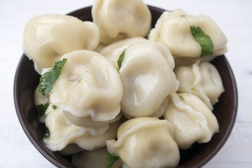 Appetizing dumplings with meat, parsley, on a light wooden background close-up.