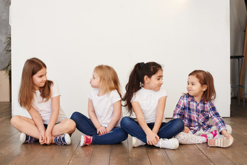 four little girls of a friend sitting on a white background happy relationships