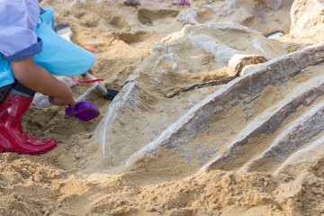 Fototapeta na wymiar Children are learning dinosaur remains, Excavating dinosaur fossils simulation in the park.