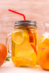 Refreshing cold detox from apples, peaches and citrus fruits in a glass on a table with fruit