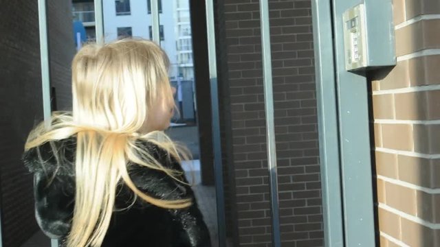 woman dials an apartment code on an electronic doorphone panel