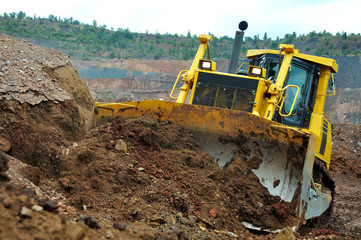Bulldozer operation in the ore quarry. Clearing the embankment with a bucket. © Yevhen