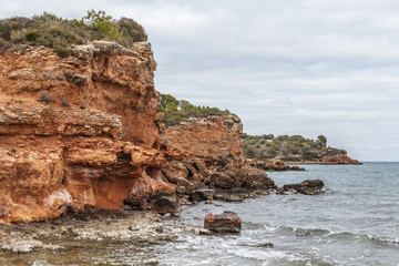 Fototapeta na wymiar Mediterranean cliffs, orange rocks, coastilne of Ampolla de Mar, Costa Daurada, province Tarragona, Catalonia, Spain.