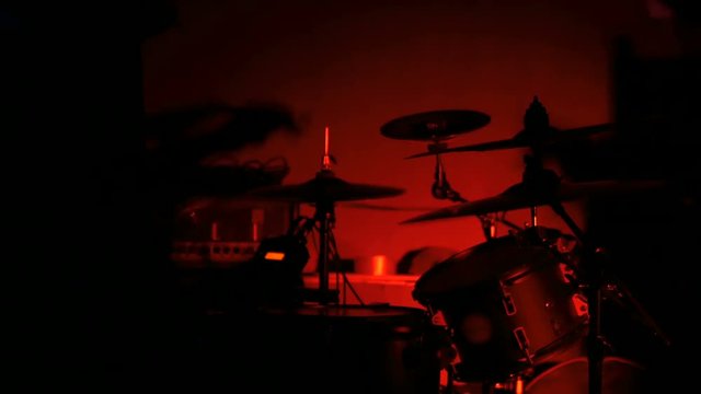 Unrecognizable male drummer silhouette playing the drums. Red light, low key. Entertainment and art concept