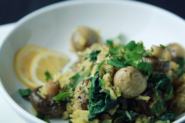 Yellow rice with mushrooms and spinach. Vegan dish. European cuisine. Vegetarian turmeric rice in the white bowl. Close up. Toned photo.