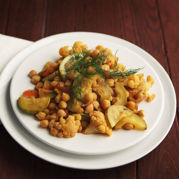 Vegetable stew with chickpeas, cauliflower and cabbages. Close up. Vegan dish. European cuisine. Vegetarian lunch. Toned photo.