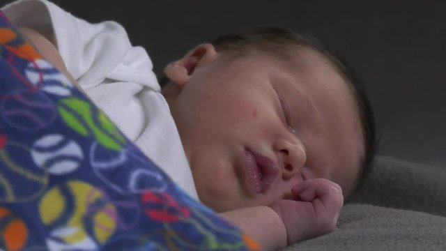 newborn baby sleeping comfortably under blanket with smooth movement