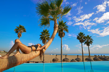 woman lying on pool bent palm tree trunk