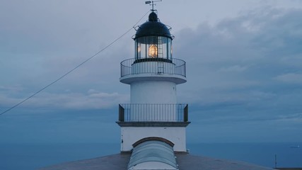 Beautiful and symmetrical dawn shot of lighthouse tower on edge of cliff, beaming and projecting ray of light in soft and blue shades of sunset evening. peace harmony and balance with pastel palette