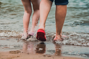 people's legs walking in sea waves on the seacoast