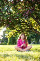 Pretty smiling girl in pink blossom garden. Family Holiday