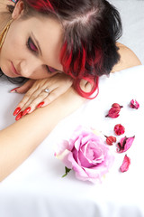 Naklejka na ściany i meble Woman face with long black and red hair lying on her hands with flowers