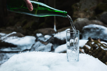Mineral mineral water is poured from a glass green bottle into a clear glass beaker.