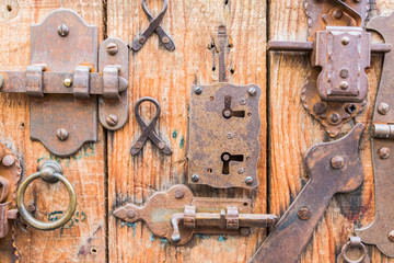 Different lockers, knobs and iron hinges on wooden door..