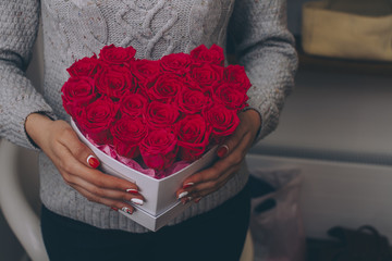 Box with red roses in female hands