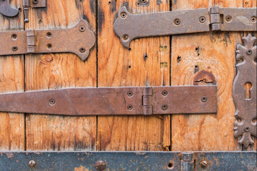 Different lockers, knobs and iron hinges on wooden door..