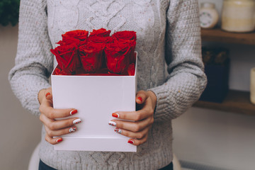 Bouquet of red roses in a gift box in female hands