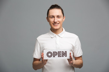 Cheerful young man showing blank Open.