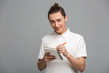 Cheerful young man writing notes in notebook.