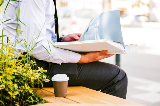 Young Businessman Drinks Coffee to Go While Sitting Outdoor