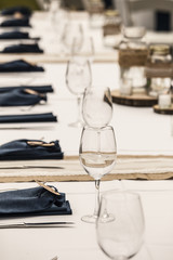 Row of glasses and burlap details for wedding reception table.