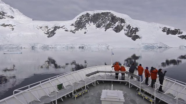 Panning across a ship's bow with tourists in the Lemaire Channel in Antarctica. 