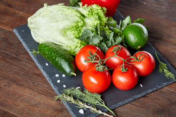 Vegetarian still life of assorted fresh vegetables and herbs on vintage wooden background, top view, selective focus.