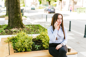Fototapeta premium Young beautiful businesswoman drinks coffee and use cellphone
