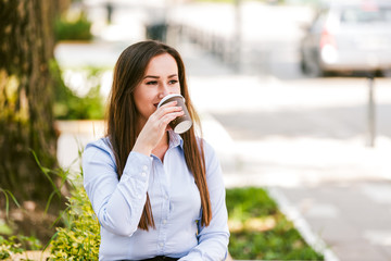 Beautiful businesswoman drinks coffee to go