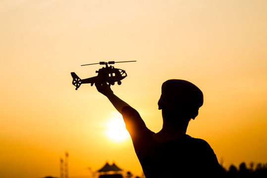 Silhouette boy playing  helicopter model with sun set.