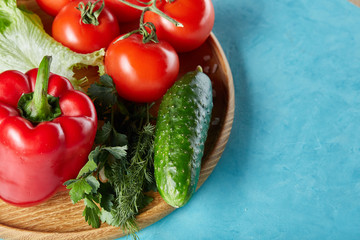 Refreshing close-up still life of assorted fresh vegetables and herbs on blue background, top view, selective focus.