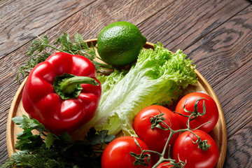 Close-up still life of assorted fresh vegetables and herbs on vintage wooden background, top view, selective focus.