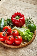 Artistic still life of assorted fresh vegetables and herbs on rustic wooden background, top view, selective focus.