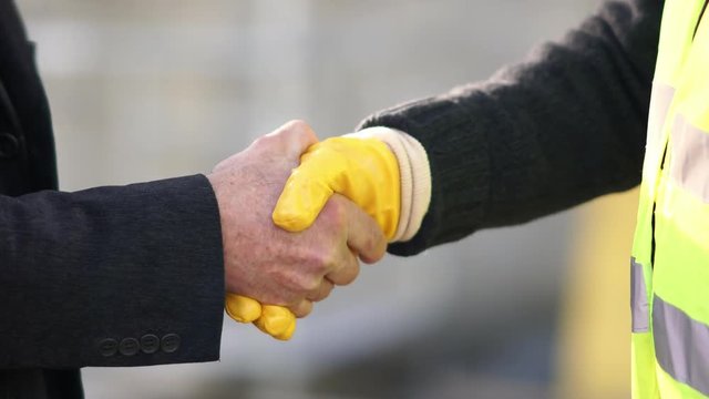 Construction worker and engineer shaking hands at construction site